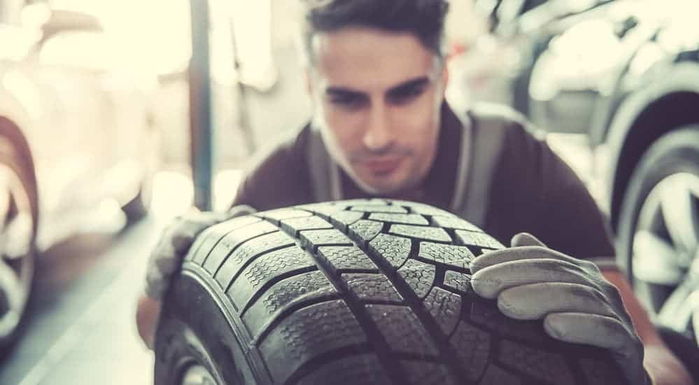 A mechanic is inspecting a car's tire.