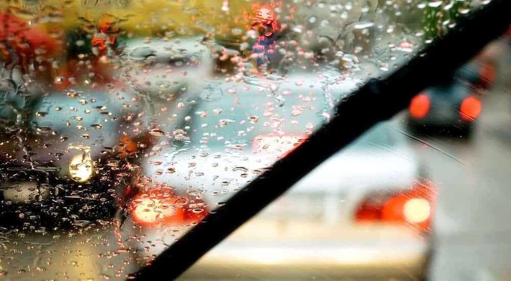 A wiper blade is shown in use on a rainy windshield from the inside of the car.
