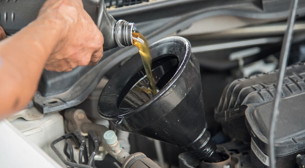 Hands pouring oil into a funnel as part of an oil change