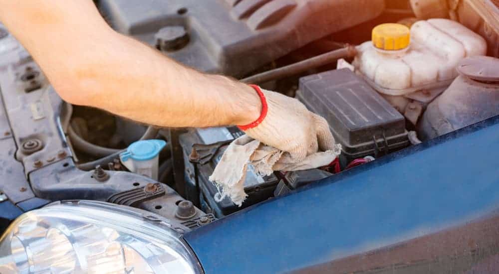 A person is cleaning their car battery with a rag.