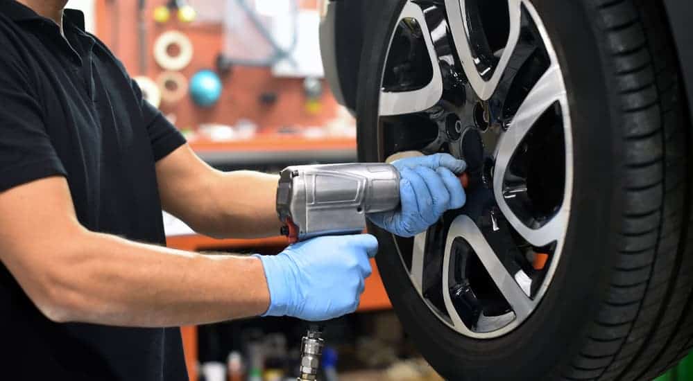 A mechanic is using an impact wrench to replace the tire on a customer's car.