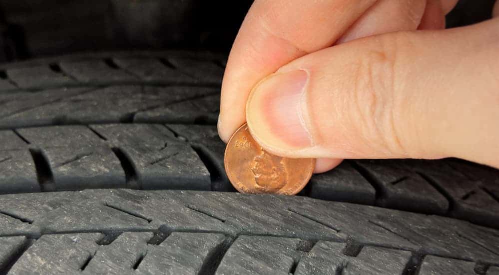 Someone is holding a penny between a tire's tread to check the ware.