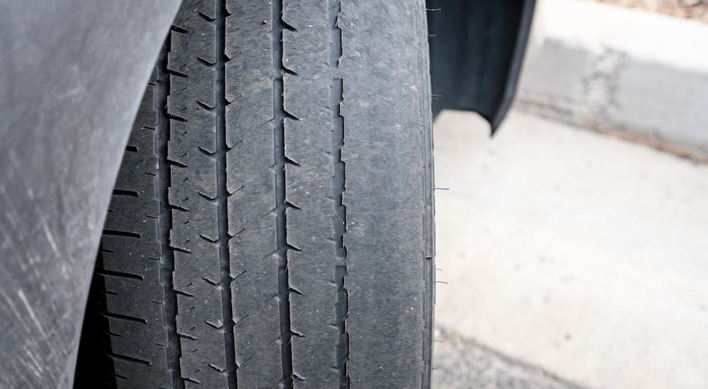 A tire with worn treads is turned out from a car.