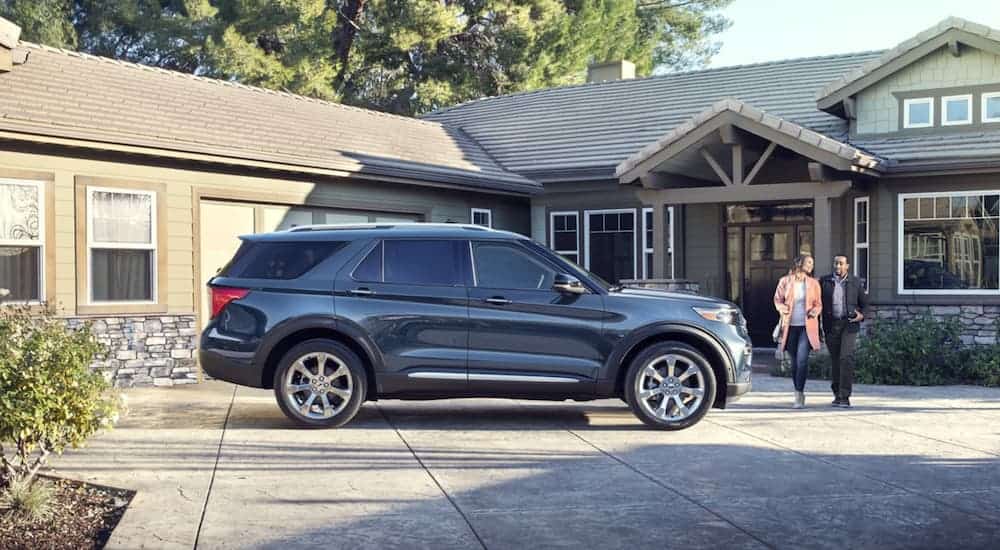 A blue 2020 Ford Explorer is outside a home as a couple walks toward it.