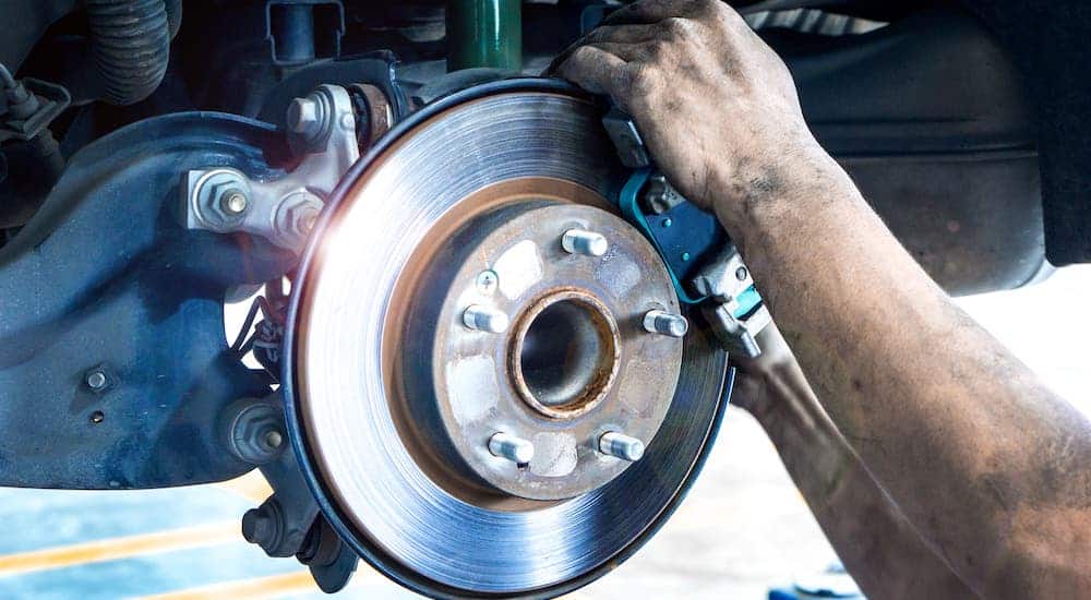 Hands are shown changing the brake pads on a car as part of a Ford service near you.