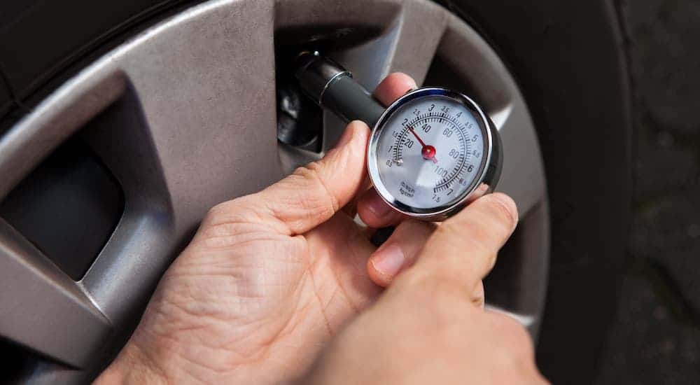 A closeup shows hands checking the pressure of a tire.