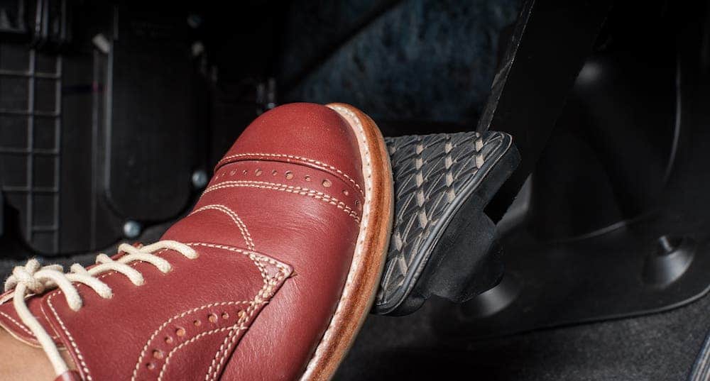A closeup shows a red shoe on a brake pedal.